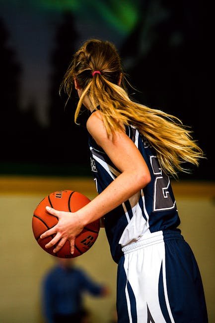 A young female basketball player holding a ball during an indoor game.